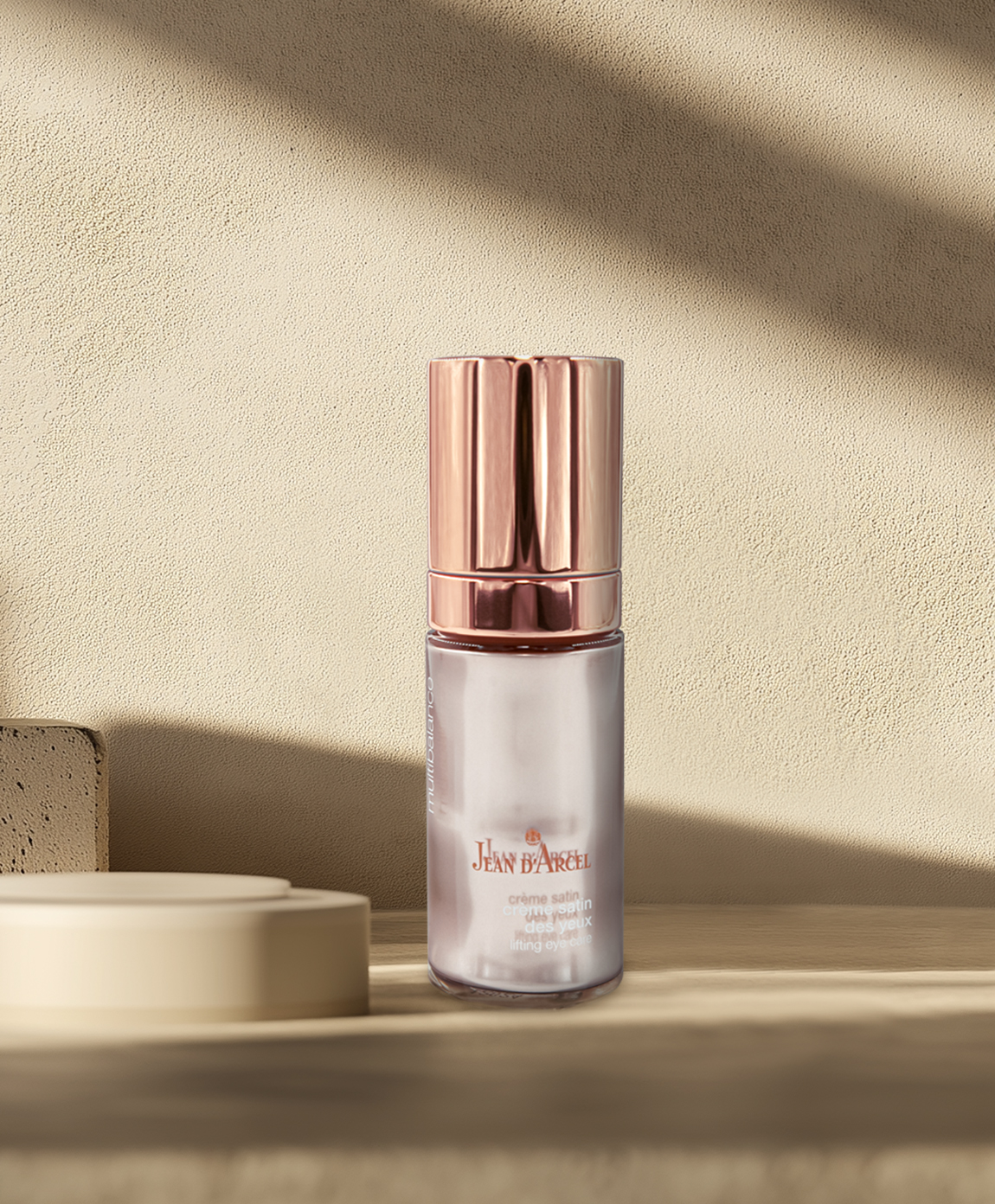 Augencreme-Flaschemit roségoldenem Deckel vor beigefarbenem Hintergrund.